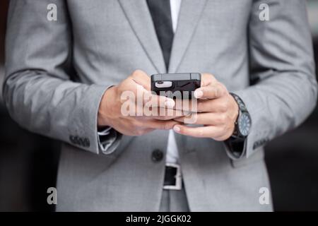 Waiting for my lift. an unrecognizable businessman standing and using his cellphone in the city. Stock Photo