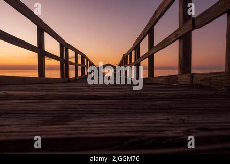 The last light of the setting sun colors the sky above a pier in Fairhope, Alabama. Stock Photo