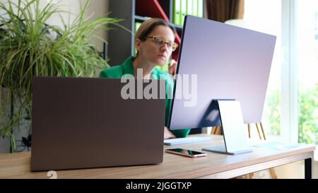 Woman office worker sitting at workplace and working using pc Stock Photo