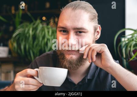 Portrait of a young bearded man with a cup of tea. Stock Photo