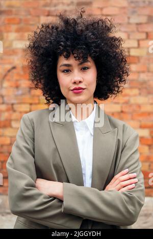 young woman looking at camera with arms folded Stock Photo