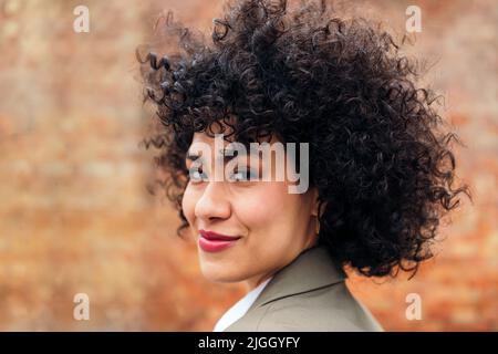 portrait of a young woman with curly hair smiling Stock Photo