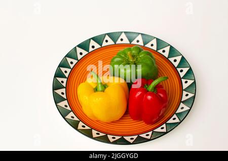 Fresh Green, Red and Yellow capsicum in a colourful plate on the white background Stock Photo