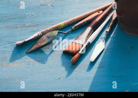 Artistic art supply utensils with paintbrushes on turquoise wooden background with copy space. Stock Photo