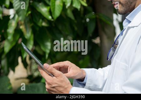 Cropped photo of a male biologist using a digital tablet in a greenhouse Stock Photo