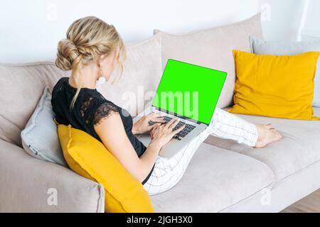 Caucasian woman using laptop wireless apps browsing internet sitting on sofa smiling middle aged businesswoman working remotely on computer surfing internet, chatting online, looking at screen at home Stock Photo