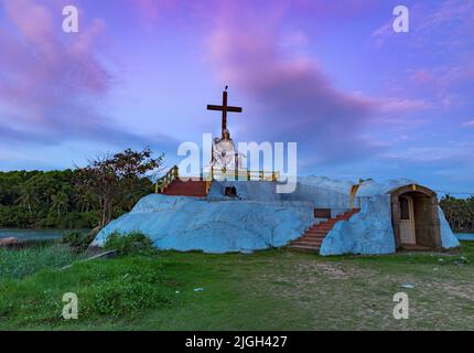 Saint Mary and Jesus Statue with a Cross in Poovar Lake, on a colorful sky background. Thiruvananthapuram, Kerala, India. Stock Photo