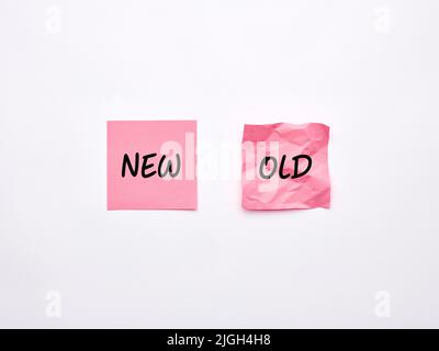 The words old and new on pink sheets of note paper on white background. Stock Photo