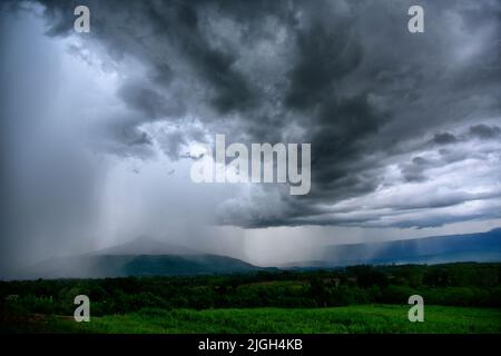 Before a heavy rainstorm, the sky was covered with clouds and strong winds, the dark clouds looked like huge black smoke from an erupting volcano. Con Stock Photo