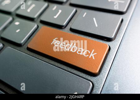 press orange feedback button on laptop keyboard. feedback inscriptions on the keyboard button close up Stock Photo