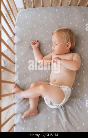 Upper view portrait of little baby boy in diaper lying in his bed napping watching sweet dreams. Safe child sleep. Childcare concept. Happy childhood Stock Photo