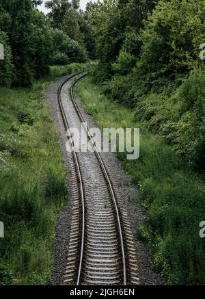 railway tracks passing through green trees. No traffic. Empty winding railway tracks Stock Photo