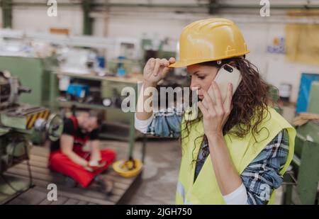 Woman is calling ambulance for her colleague after accident in factory. First aid support on workplace concept. Stock Photo