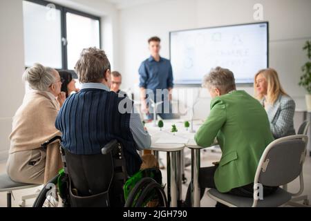 Group of senior students discussing about altenrative energy with teacher in classroom. Stock Photo