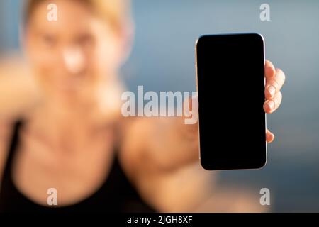 Unrecognizable Smiling Woman Showing Smartphone With Blank Screen While Standing Outdoors Stock Photo