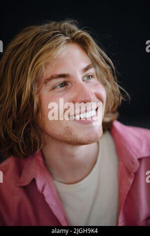 Portrait of confident handsome young man looking away on black background, close-up Stock Photo