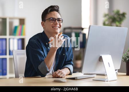 Inspiration Concept. Smiling Young Businessman Sitting At Workplace And Looking Away Stock Photo