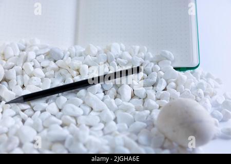 Notebook and pen on white studio background. White rocks falling in front of it. Beautiful composition of notebook, pen. High quality photo Stock Photo