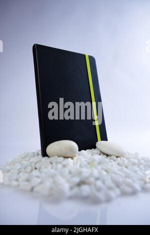 Black notebook on a mountain stack of white rocks. Beautiful studio product photoshoot. High quality photo Stock Photo