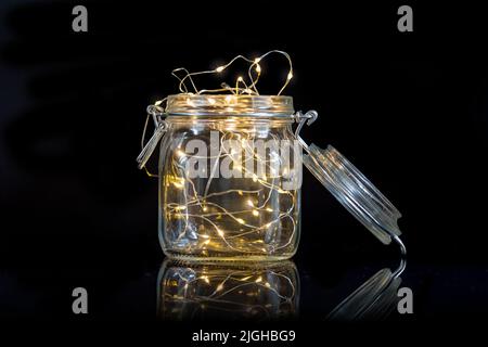 string lights in an open mason jar isolated on black background Stock Photo