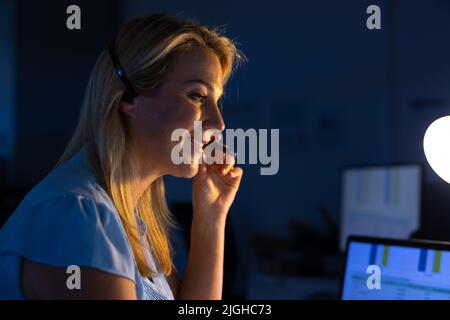 Smiling caucasian female customer service representative communicating over headset in office Stock Photo