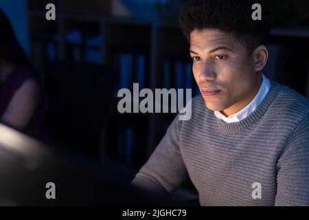 Serious asian businessman using computer while working late in office at night Stock Photo