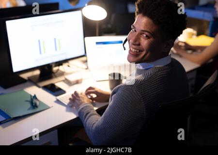 Portrait of happy male asian customer service representative wearing headset using computer on desk Stock Photo