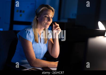 Caucasian female customer service representative talking with customer over headset in office Stock Photo