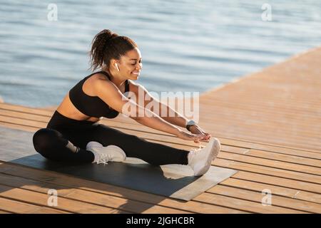 African american woman doing workout outdoors, listening to music Stock Photo