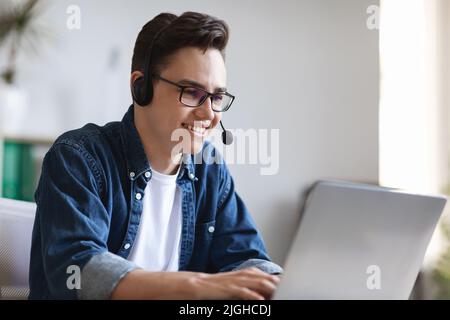 Hotline Concept. Smiling Call Center Operator In Headset Working With Laptop Stock Photo