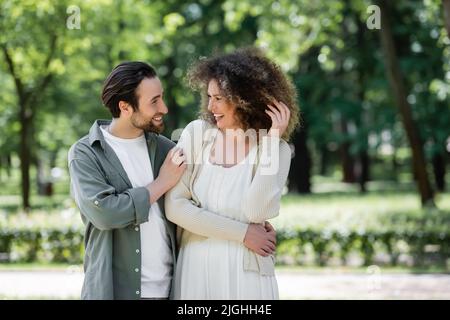 joyful young couple smiling and looking at each other in summer park Stock Photo