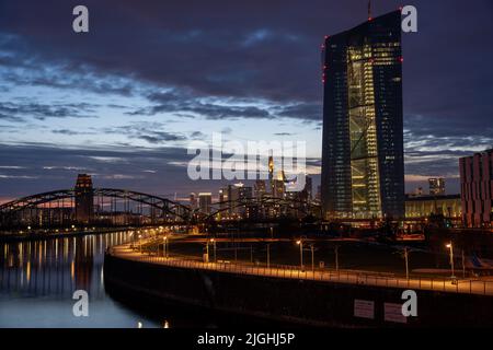 Blick auf die Europäische Zentral Bank bei Nacht. Im Hintergrund sieht man die Skyline von Frankfurt am Main Stock Photo