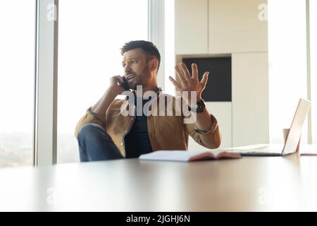 Discontented Businessman Talking On Cellphone Solving Business Problems In Office Stock Photo