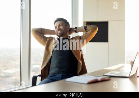 Happy Male Entrepreneur Relaxing In Chair Sitting In Office Stock Photo
