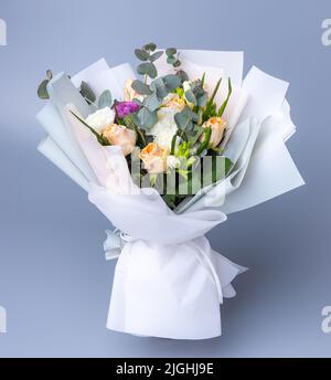 Delicate holiday bouquet wrapped in bright floral paper on a blue  background Stock Photo - Alamy