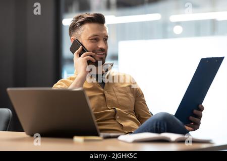 Entrepreneur Man Talking On Phone Holding File Binder In Office Stock Photo