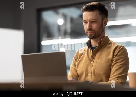 Businessman Working Online Using Laptop Computer Sitting In Modern Office Stock Photo
