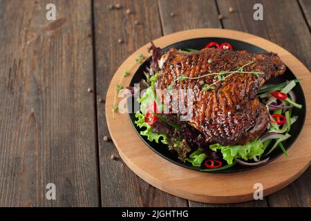 Portion of roasted duck leg on wooden table, decorated with pepper, copyspace Stock Photo