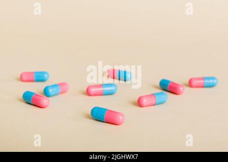Heap of pink and blue pills on colored background. Tablets scattered on a table. Pile of red soft gelatin capsule. Vitamins and dietary supplements co Stock Photo