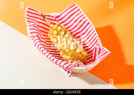 Delicious Crunchy Korean Style Chunky Potato Corn Dogs with Batter and Fried Potatoes. Isolated on Orange  Background with Copy Space for Text Stock Photo