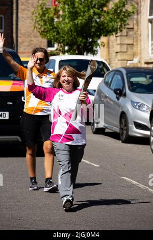 The Friendly Bench founder, Lyndsey Young carries the Queens Baton along Avenue road, Grantham, Lincolnshire, England. The Baton is en route to the 16 Stock Photo