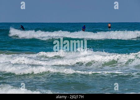 Surfers in the water on the waves of the Mediterranean Sea. Stock Photo