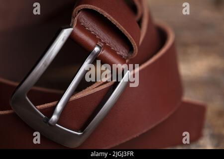 Men's leather trouser red belt in the background of aged wood. Men's fashion accessories closet. Genuine leather, handmade Stock Photo