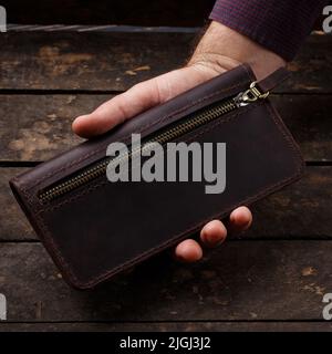 Leather brown men's wallet in a man's hand on a vintage wooden background  Stock Photo - Alamy