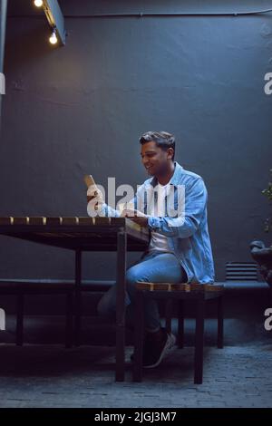 Coffee shot uploading to the social media. a handsome young man sitting alone in a cafe and using his cellphone while enjoying a coffee. Stock Photo