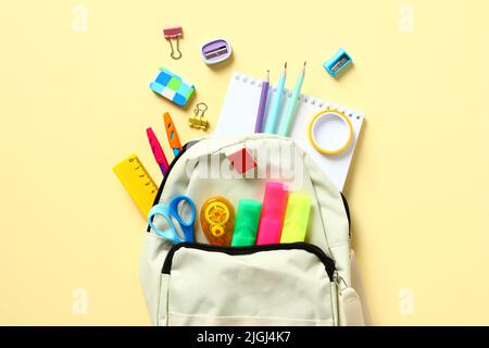 Backpack with colorful school supplies on yellow table, top view. Back to school concept. Flat lay, top view. Stock Photo