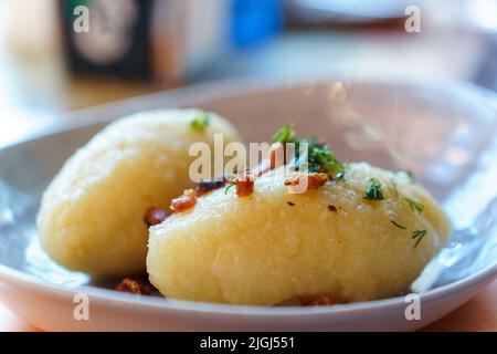 National Lithuanian cuisine. Zepelins with cracklings and greens in a plate. Stock Photo