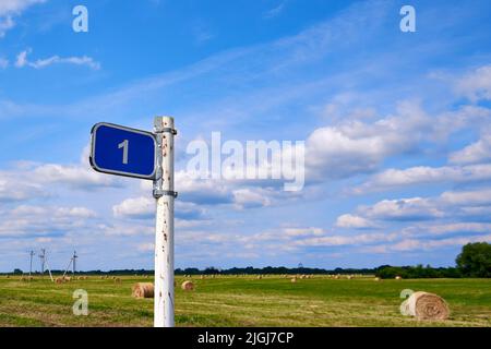 Distance road sign. Sign 1 kilometer against the blue sky and summer field Stock Photo