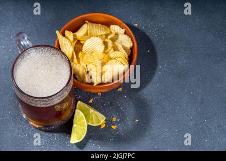 Beer with various salted snacks set. Black table background with traditional party snacks, beer bottles and glasses, with chips, onion rings, salted n Stock Photo