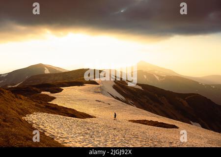 View of the grassy hills and snowy mountains on background. Dramatic spring scene. Landscape photography Stock Photo